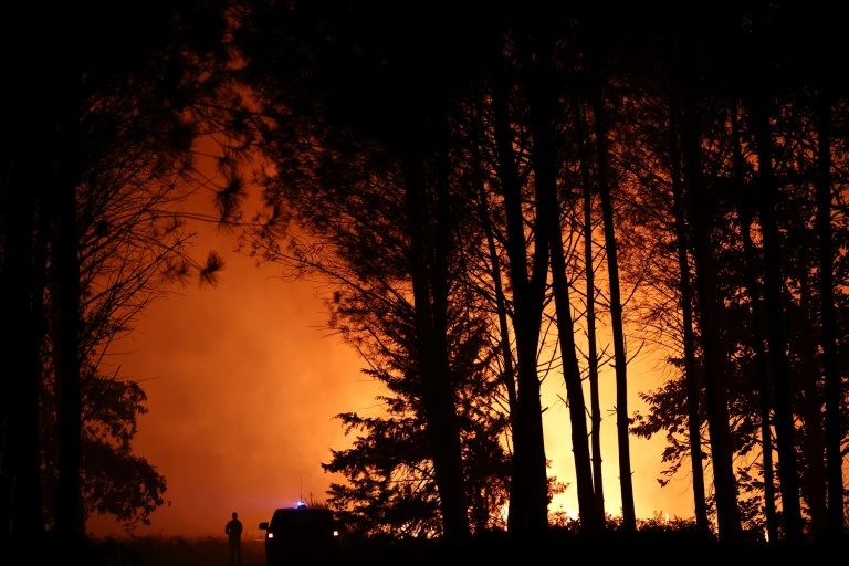 Un pompier observe un incendie de forêt qui fait rage près de Luglon, dans les Landes, le 13 août 2026