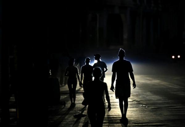 Des habitants marchent dans une rue de La Havane pendant une panne d'électricité, le 13 mai 2026 à Cuba