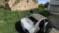 Un Palestinien à proximité d'un véhicule calciné après une attaque attribuée à des colons israéliens à Jalud, près de Naplouse, en Cisjordanie occupée, le 22 mars 2026