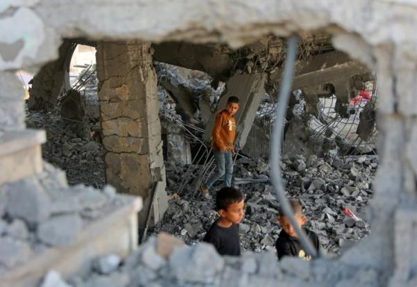 Des garçons marchent parmi les décombres d’un bâtiment endommagé, qui abritait des personnes déplacées dans le quartier de Zeitoun, à Gaza-Ville, le 20 novembre 2025, au lendemain d'une frappe israélienne