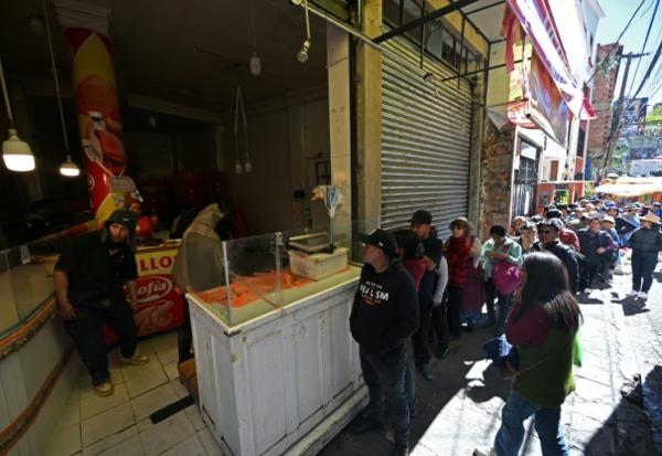 Des habitants font la queue pour acheter du poulet sur un marché touché par les pénuries dues aux barrages routiers et aux manifestations contre le président Rodrigo Paz, le 19 mai 2026 à La Paz, en Bolivie