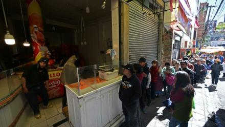 Des habitants font la queue pour acheter du poulet sur un marché touché par les pénuries dues aux barrages routiers et aux manifestations contre le président Rodrigo Paz, le 19 mai 2026 à La Paz, en Bolivie