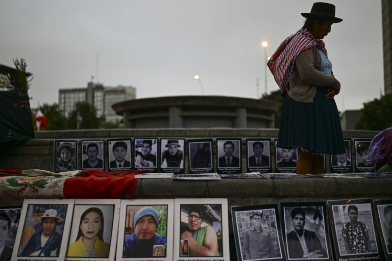 Une personne se tient à côté de photographies de victimes de crimes imputés à l'Etat péruvien, lors d’une veillée devant le Palais de Justice à Lima, le 27 juillet 2026