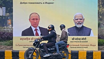 Un motard passe devant des portraits du président russe Vladimir Poutinen, à gauche, et du Premier ministre indien Narendra Modi, à droite, à New Delhi le 4 décembre 2025