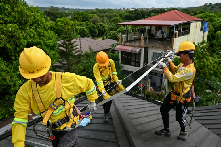 Des ouvriers installent des panneaux solaires sur un toit à Carmona, aux Philippines, le 9 juillet 2026