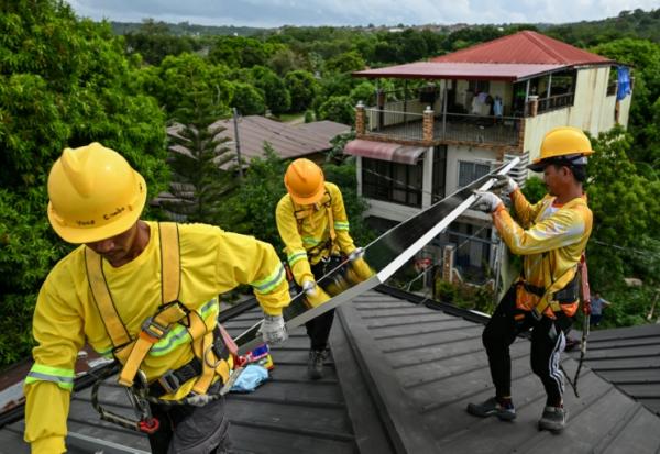 Des ouvriers installent des panneaux solaires sur un toit à Carmona, aux Philippines, le 9 juillet 2026