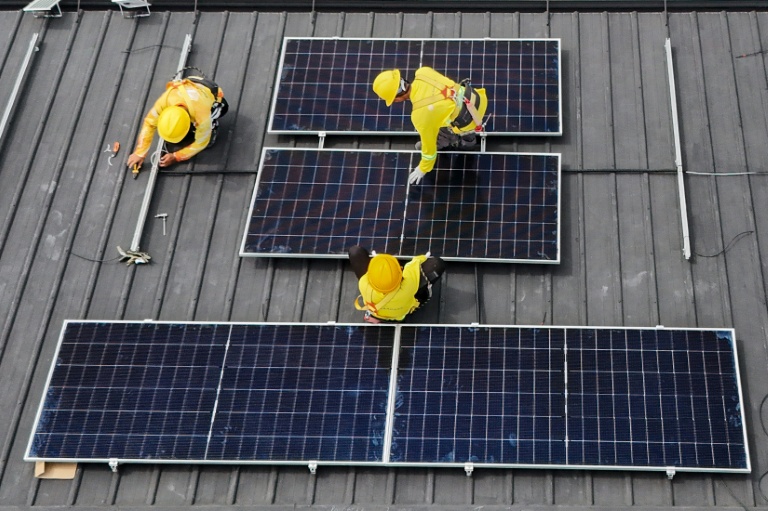 Vue aérienne montrant des ouvriers qui installent des panneaux solaires sur un toit à Carmona, aux Philippines, le 9 juillet 2026