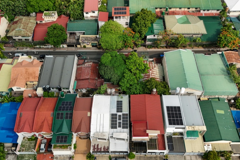 Vue aérienne montrant des panneaux solaires sur les toits de maisons dans un quartier résidentiel, le 7 juillet 2026 à Manille
