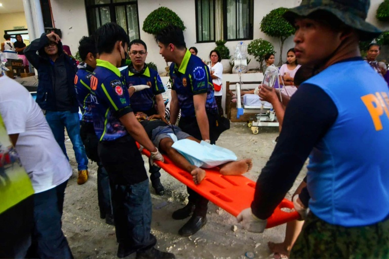Les policiers et les secouristes transportent une personne blessée à l'hôpital de la ville de Bogo, province de Cebu, dans le centre des Philippines, le 1er octobre 2025, après un puissant séisme