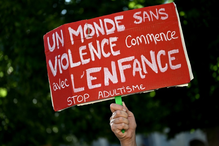 Un manifestant tient une pancarte contre les violences faites aux enfants lors d'une manifestation à Bordeaux le 15 juin 2026 après le décès de Lyhanna