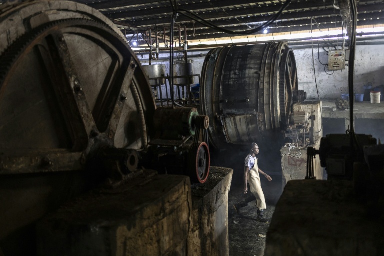 Un ouvrier d'usine marche entre des fûts à l'usine Z-Tannery de Kano, le 11 septembre 2025. Kano, centre historique du cuir, approvisionne des géants du luxe tels que Louis Vuitton, Gucci et Ralph Lauren, le Nigeria exportant près de 90 % de ses peaux à l'étranger. Mais comme la finition est effectuée en Europe, le label 