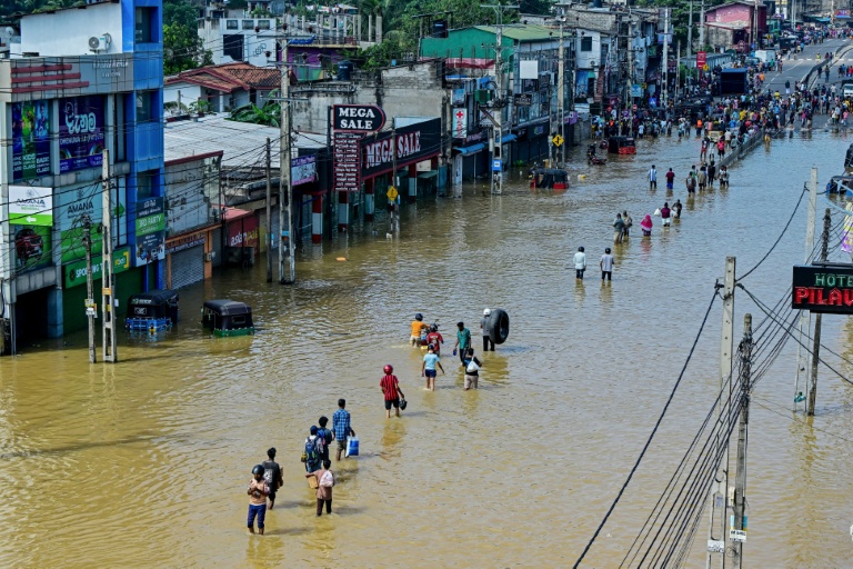 Des personnes traversent une rue inondée après de fortes pluies à Wellampitiya, près de Colombo, au Sri Lanka, le 30 novembre 2025