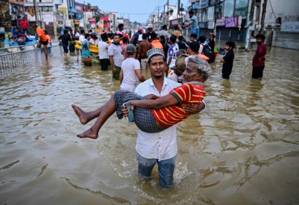 Un homme porte une personne âgée dans une rue inondée, le 30 novembre 2025 à Wellampitiya au Sri Lanka