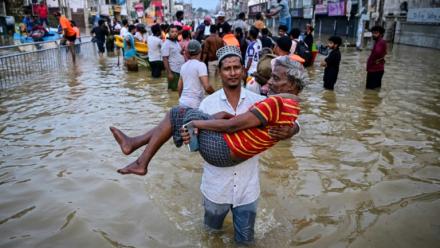 Un homme porte une personne âgée dans une rue inondée, le 30 novembre 2025 à Wellampitiya au Sri Lanka