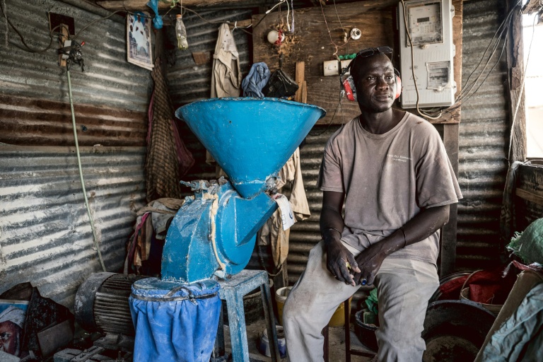 Amadou Gaye, 40 ans, est assis à côté d'une machine à moudre le millet dans sa boutique à Sukuta, en Gambie, le 12 septembre 2026