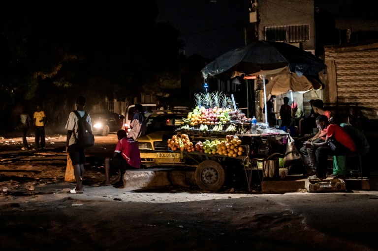 Un vendeur de fruits attend des clients à son étal lors d'une coupure d'électricité à Westfield, en Gambie, le 12 septembre 2026, alors que des coupures prolongées perturbent les activités commerciales et la vie quotidienne dans tout le pays