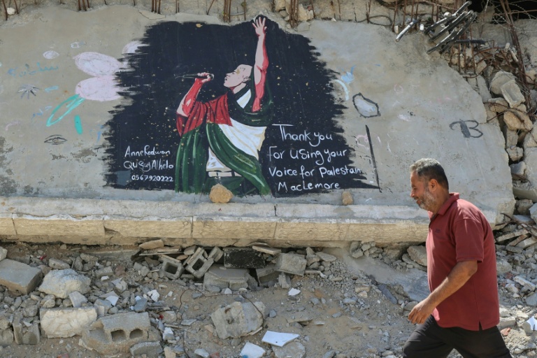 Un homme marche à proximité d'une fresque représentant l'artiste Macklemore, le 19 septembre 2026 à Gaza