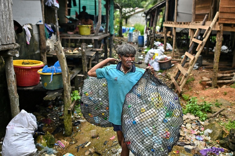 En Thailande, sur l'île de Koh Chang, un pêcheur montre un sac de déchets plastiques qu'il s'apprête à vendre à une ONG qui produit des granulés de plastique recyclé,le 24 septembre 2024 (ARCHIVES)
