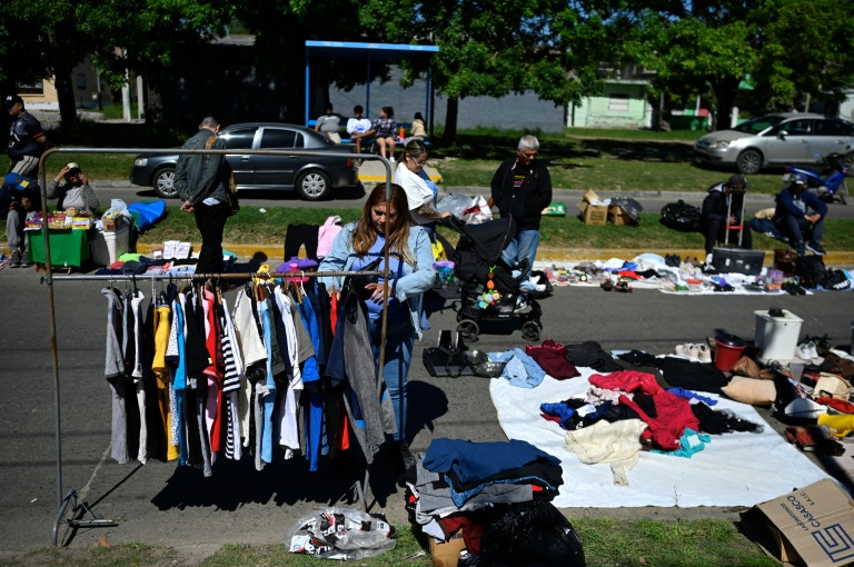 Une passante regarde des vêtements d'occasion sur un marché de rue à Villa Fiorito, dans la banlieue de Buenos Aires, le 19 octobre 2025 en Argentine