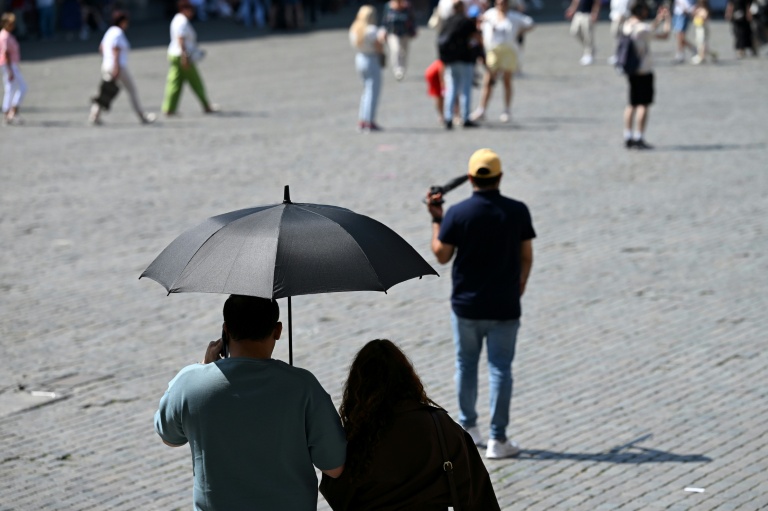 Des touristes visient Bruxelles à l'abri sous un parapluie pour se protéger du soleil lors d'une vague de chaleur le 27 mai 2026, en Belgique