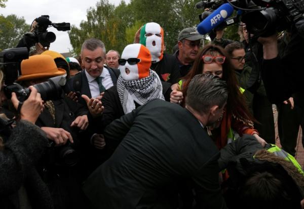 Les membres du groupe Kneecap, dont le chanteur Liam O'Hanna, alias Mo Chara, portent des cagoules aux couleurs du drapeau irlandais à leur arrivée au tribunal de Woolwich, à Londres, le 26 septembre 2025