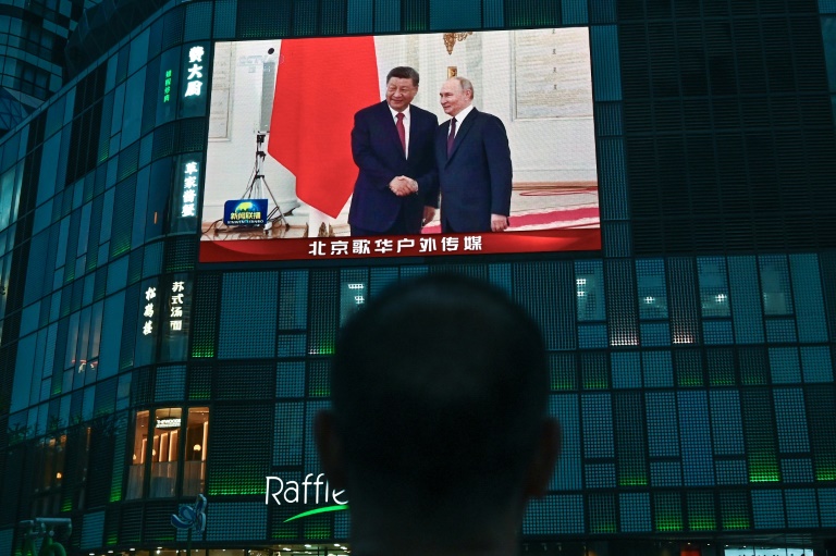 Les présidents russe Vladimir Poutine (d) et chinois Xi Jinping à Moscou sur un écran posé contre la façade d'un centre commercial à Pékin, le 8 mai 2025