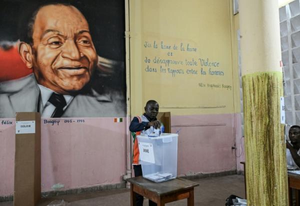 Un représentant de la commission électorale compte les votes de la présidentielle ivoirienne devant un tableau du premier président de Côte d'Ivoire, Félix Houphouët-Boigny, le 25 octobre 2025 à Abidjan