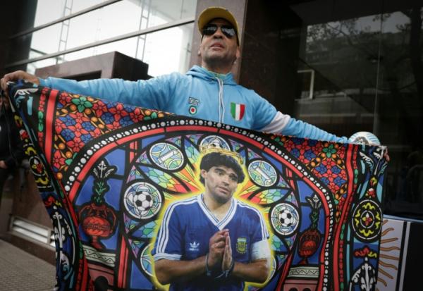 Un fan tient un drapeau à l'effigie de la légende du football argentin Diego Maradona devant le tribunal à San Isidro, le 8 octobre 2026 en Argentine