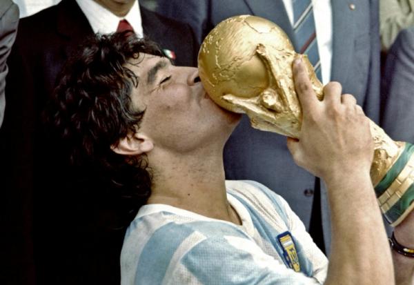 Sur cette photo prise le 29 juin 1986, la star du football argentin et capitaine de l'équipe, Diego Maradona, embrasse la Coupe du monde remportée par son équipe après une victoire 3-2 contre l'Allemagne de l'Ouest au stade Azteca à Mexico