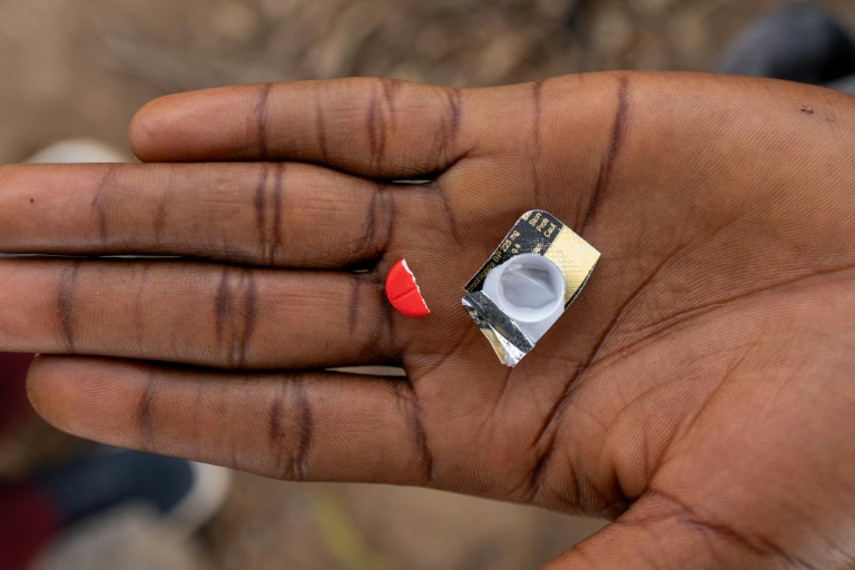 Un toxicomane tient la moitié d'un comprimé rouge à base de tapentadol à Abuja, le 24 février 2026 au Nigeria