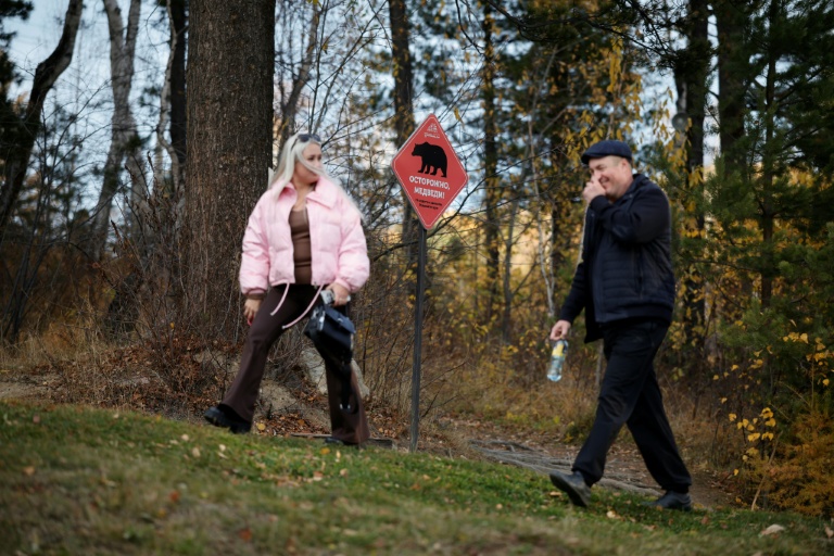 Des promeneurs passent devant un panneau avertissant de la présence d'ours sur un sentier de randonnée dans le parc national du lac Baïkal, dans la région d'Irkoutsk, le 9 octobre 2026 en Sibérie