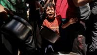 Un enfant pleure au milieu de Palestiniens qui attendent de recevoir un repas chaud distribué par une association caritative locale à Nousseirat, dans le centre de la bande de Gaza, le 24 mai 2025