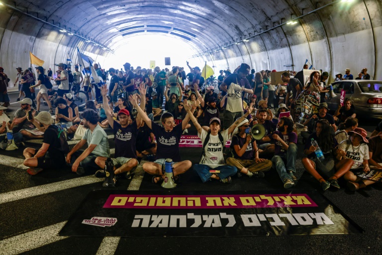 Des familles des otages retenus dans la bande de Gaza et leurs partisans bloquent la circulation dans un tunnel lors d'une manifestation pour réclamer la libération des otages, le 17 août 2025 à Jérusalem