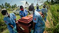 Des membres d'une équipe de la Croix-Rouge congolaise transportent le cercueil d'une femme qui serait décédée des suites de la maladie à virus Ebola lors de son enterrement dans les règles de sécurité dans un cimetière de Bunia, en RDC, le 7 juin 2026.
