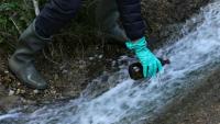 Un bénévole d'une association écologique prélève des échantillons d'eau dans les rejets d'une usine fabriqunate des molécules de type PFAS pour les industries pharmaceutique et des pesticides, le 18 avril 2024 à Salindres, dans le Gard 