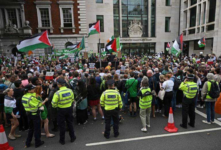 Des policiers encadrent une manifestation de soutien au trio nord-irlandais Kneecap, et à son chanteur Liam O'Hanna alias Mo Chara, où des drapeaux palestiniens sont agités, à Londres le 20 août 2025
