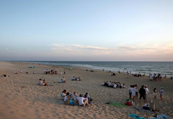 Des personnes vêtues de blanc rassemblées sur la plage du Porge pour soutenir les commerces de la commune, le 7 août 2026, en Gironde
