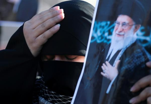 Une femme irakienne chiite se tient la tête en brandissant une photo du guide suprême iranien Ali Khamenei, tué la veille dans une opération israélo-américaine, le 1er mars 2026 à Bagdad