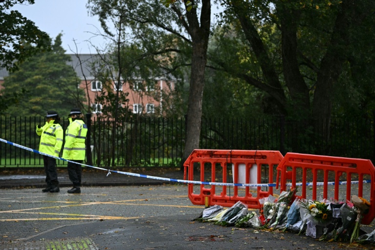 Des policiers près de fleurs déposées à l'extérieur de la synagogue d'Heaton Park, à Crumpsall, au nord de Manchester, le 4 octobre 2025 en Angleterre