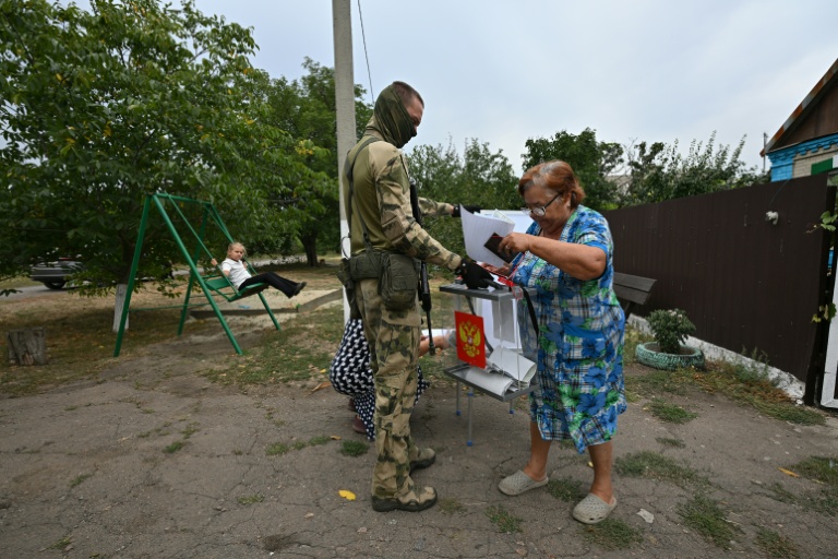 Une électrice glisse son bulletin dans une urne mobile à l'occasion d'un vote anticipée pour les législatives russes dans la région occupée de Donetsk, dans l'est de l'Ukraine, le 15 septembre 2026