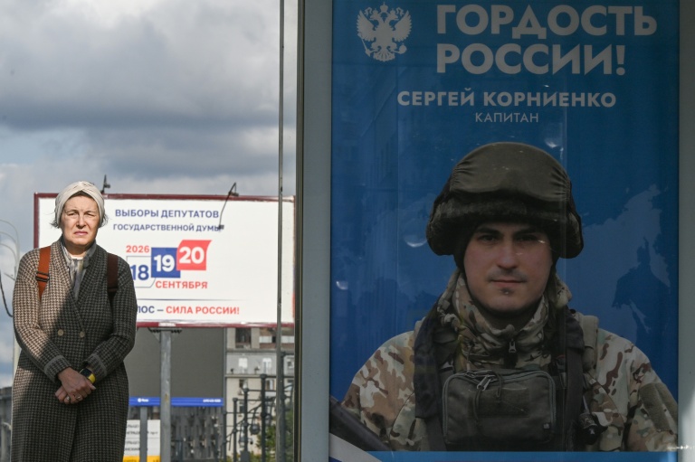 Une passante près d'une affiche faisant la promotion de l'armée russe en Ukraine sur laquelle on peut lire 