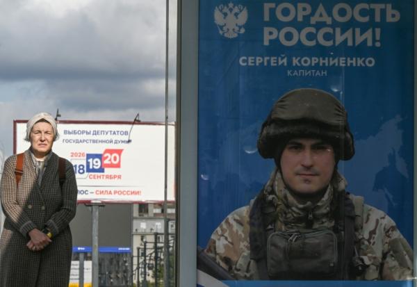 Une passante près d'une affiche faisant la promotion de l'armée russe en Ukraine sur laquelle on peut lire "Fierté de la Russie", à Moscou le 15 septembre 2026