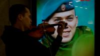Un musicien de rue devant uen affiche encouregeant à s'engager dans l'armée, dans le métro de Moscou le 2 juin 2023