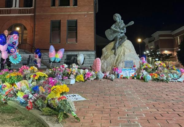 Au pied de la statue de Dolly Parton, des fleurs déposées en hommage le 25 août 2026 à Sevierville (Etats-Unis)