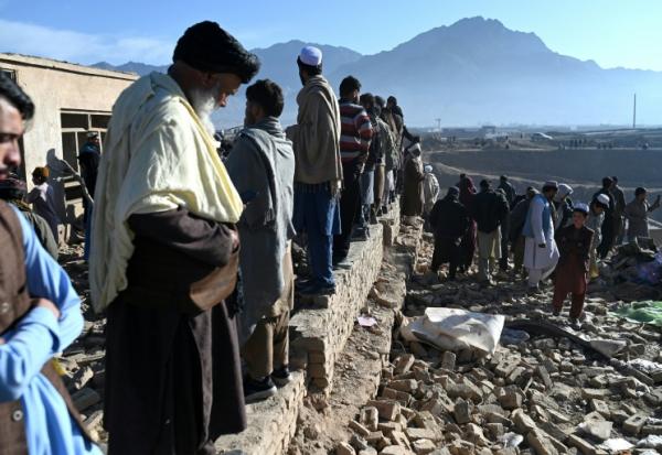 Des habitants rassemblés autour d'habitations endommagées après des bombardements, en périphérie de Kaboul, le 13 mars 2026 en Afghanistan