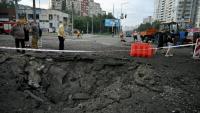 Des habitants de Kiev passent près d'un cratère causé par une frappe de missile russe sur la capitale de l'Ukraine, le 11 juillet 2026