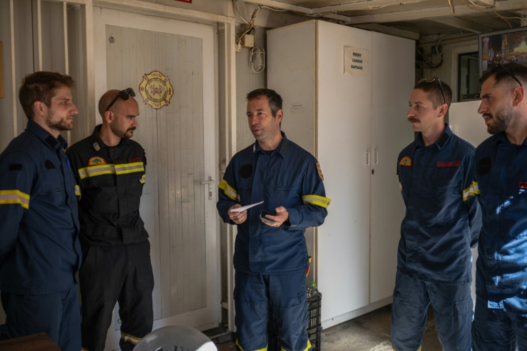 Apollos Kounis (c), chef d'un groupe local de pompiers volontaires, donne des instructions pour un dernier exercice de la saison avant de commencer le mois prochain les quarts de 24 heures au poste d'urgence, à Rodopoli, dans la banlieue d'Athènes, le 18 mai 2025 en Grèce
