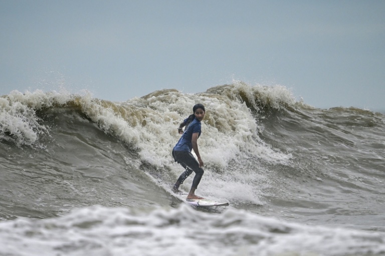 La surfeuse bangladaise Fatima Akhter pratique son sport à Cox's Bazar, dans le sud-est du Bangladesh, le 22 juin 2026  