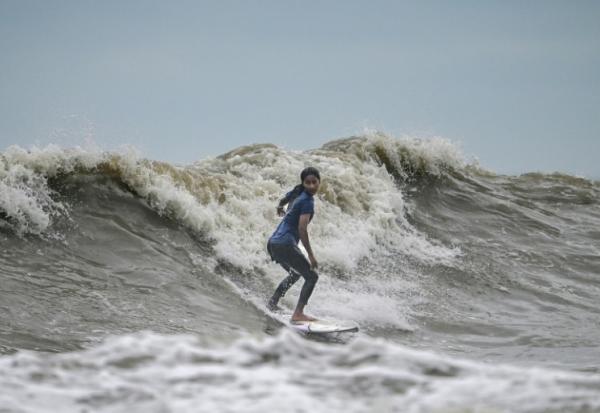 La surfeuse bangladaise Fatima Akhter pratique son sport à Cox's Bazar, dans le sud-est du Bangladesh, le 22 juin 2026  