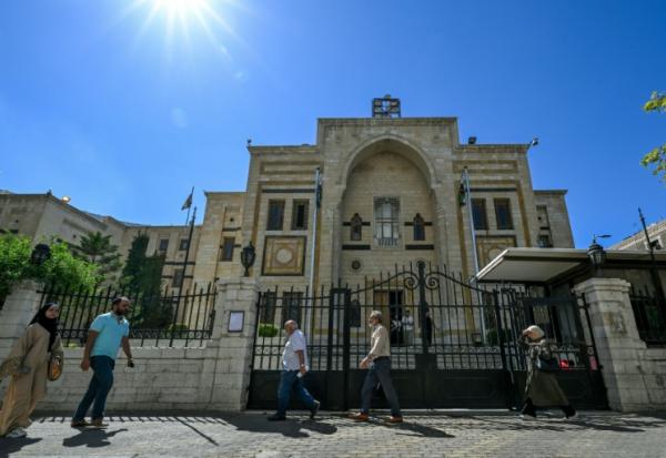 Des personnes passent devant le bâtiment du Parlement à Damas, le 1er octobre 2025